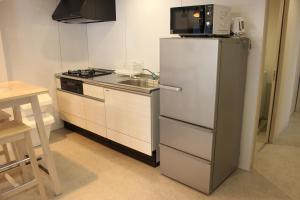 a kitchen with a white refrigerator and a sink at Hotel Flap Resort in Chatan
