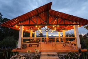 a large wooden pavilion with a table and lights at Hospedaje Rancho La Joya in Villa del Carbón