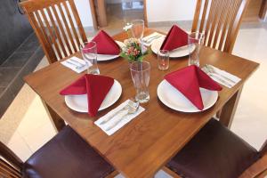 una mesa de madera con platos y servilletas rojas. en The Sarining Hotel en Tabanan
