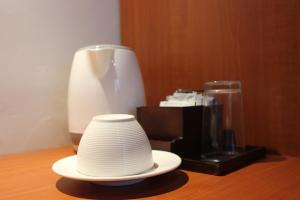 塔巴南的住宿－The Sarining Hotel，坐在咖啡壶旁边的桌子上的帽子