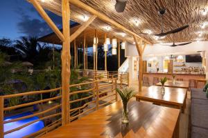 un restaurante con mesas de madera y bancos en una terraza en The Nomadic Hotel, en Nosara