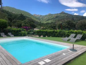 einen Pool mit Stühlen und Bergen im Hintergrund in der Unterkunft Chez Muriel in Porto-Vecchio