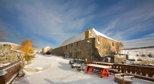 ein Gebäude im Schnee mit einem Tisch und Bänken in der Unterkunft Le Francillon in Les Estables