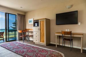 Habitación de hotel con escritorio y TV de pantalla plana. en Pebble Beach Motor Inn en Napier