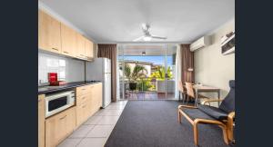 a kitchen with wooden cabinets and a living room at The Wellington Apartment Hotel in Brisbane