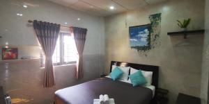 - une chambre avec un lit doté d'oreillers bleus et d'une fenêtre dans l'établissement Cola's Homestay, à Hô-Chi-Minh-Ville