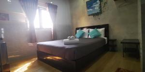 a bedroom with a bed with blue pillows and a window at Cola's Homestay in Ho Chi Minh City