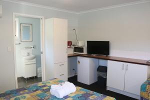 um quarto de hotel com uma cama e uma secretária com uma televisão em Agnes Palms Accommodation em Agnes Water