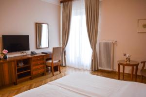 a bedroom with a bed and a desk with a television at Vila Bled in Bled
