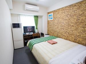a bedroom with a bed and a desk with a television at Hotel Peace Island Nago in Nago