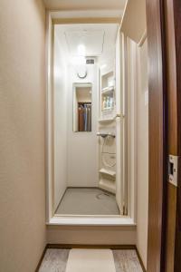a white refrigerator in a room with a door open at H2O STAY Ōtorii - Male Only in Tokyo