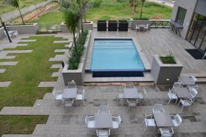 a patio with a pool and some white tables and chairs at City Lodge Hotel Maputo, Mozambique in Maputo