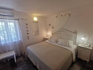 a bedroom with a bed with white sheets and a window at Ambelas Mare Apartments in Ambelas
