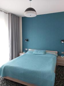 1 dormitorio con 1 cama grande y pared azul en Apartament Nadmorski - Kompleks Pięć Mórz z basenem en Sianozety