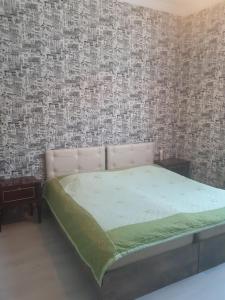 a bedroom with a bed in a room with wallpaper at Guest House Quiet Home in Batumi