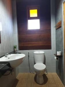 a bathroom with a toilet and a sink and a window at บ้านน่านอน in Uthai Thani