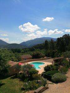 ein Schwimmbad in einem Garten mit Bergen im Hintergrund in der Unterkunft Le Voltigeur du Ventoux in Entrechaux