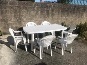 una mesa blanca con cuatro sillas alrededor en Gîte Manava - grande maison avec jardin en centre ville, en Valognes