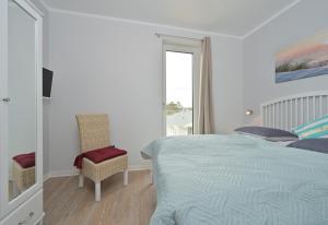 ein weißes Schlafzimmer mit einem Bett und einem Fenster in der Unterkunft BoddenPanorama in Glowe
