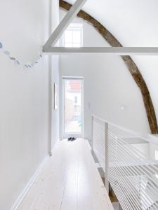 einen Flur mit weißen Wänden und eine Treppe mit einem Fenster in der Unterkunft Ferienhaus Grosse 73, Flensburg in Flensburg