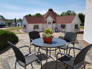 une table et des chaises avec une maison en arrière-plan dans l'établissement Landhotel Pathes Hof, à Bentwisch