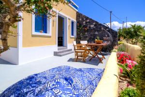 a patio with a table and chairs and a house at Pasithea Suites in Megalochori
