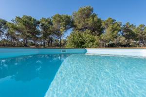 una piscina con agua azul y árboles en el fondo en Villa Del Mar Mondrago, en Palma de Mallorca