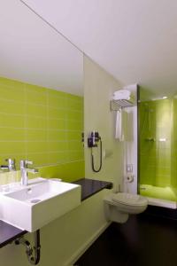 a green bathroom with a sink and a toilet at Hotel Gat Point Charlie in Berlin