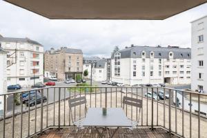 a table on a balcony with a view of a city at Le Singulier - 2 chambres et parking in Nantes