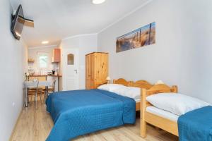 a bedroom with two beds and a kitchen with a table at Dom Gościnny Amber Dziwnów in Dziwnów