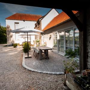 un patio con mesa y sombrilla en B&B Scheldekant, en Oudenaarde