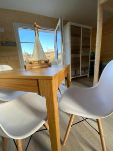 een houten tafel met twee witte stoelen en een boot erop bij Appartements Les Homards du Fier #3 in La Guérinière