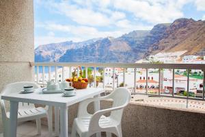 a table and chairs on a balcony with a view of mountains at Vigilia Park in Puerto de Santiago