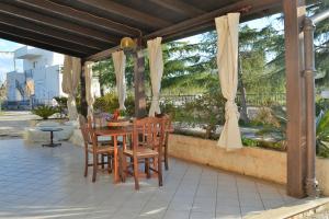 a wooden table and chairs on a patio with curtains at I Tre Coni - Villaggio di Mary in Locorotondo