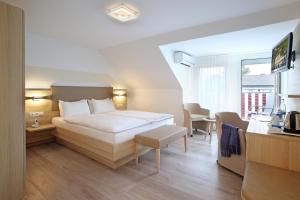 1 dormitorio con 1 cama blanca, mesa y sillas en Hotel Brenner en Koblenz
