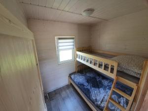 a small room with a bunk bed and a window at Domki Nadmorska fala Rusinowo in Rusinowo