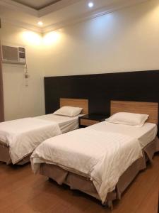2 camas en una habitación de hotel con sábanas blancas en Bait Alsadaqa Aparthotel, en Abha