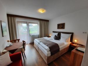ein Hotelzimmer mit einem großen Bett und einem Tisch in der Unterkunft Gästehaus Burgi in Fügen