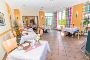 un restaurante con mesas y sillas blancas en Akzent Parkhotel Trebbin, en Trebbin