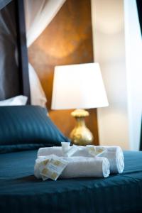 a pile of folded towels on a bed with a lamp at Le Boutique Luxury Rooms in Fiumicino