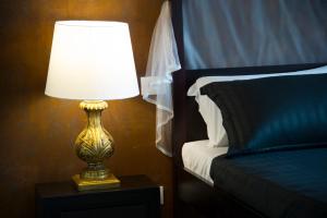 a lamp sitting on a table next to a bed at Le Boutique Luxury Rooms in Fiumicino