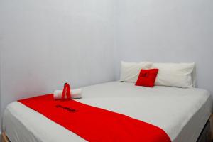 uma cama branca com um cobertor vermelho em RedDoorz At Rantepao Toraja Utara em Rantepao