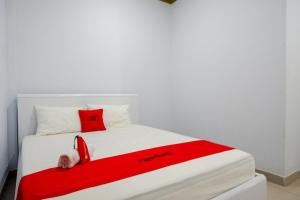uma cama com um cobertor vermelho e um telefone vermelho em RedDoorz At Rantepao Toraja Utara em Rantepao
