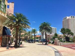 una strada cittadina con palme e edifici di Hotel Flap Resort a Chatan