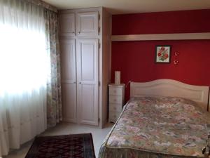 - une chambre avec un lit et un mur rouge dans l'établissement "les amandiers", à Mittelwihr