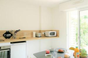 cocina blanca con microondas y mesa en Studio situé dans le centre de Saint Philibert en Saint-Philibert