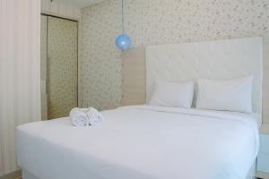 a bedroom with a white bed with two slippers on it at Best Location 1BR Apartment at Atlanta Residences By Travelio in Kukusan +15 photos
