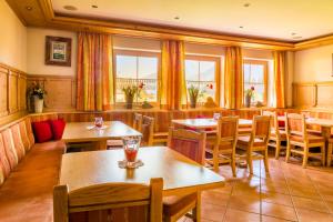 a restaurant with wooden tables and chairs and windows at Bio-Bauernhof Obertrattenbachhof in Neukirchen am Großvenediger