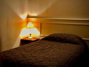 ein Schlafzimmer mit einem Bett und einer Lampe auf einem Nachttisch in der Unterkunft Le Grand Hôtel in Souillac
