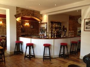 a bar with red bar stools in a restaurant at The Half Moon Inn in Woking